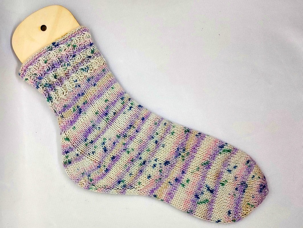Socke auf Holzsockenformer mit Ajourbündchen und gesprenkeltem Garn