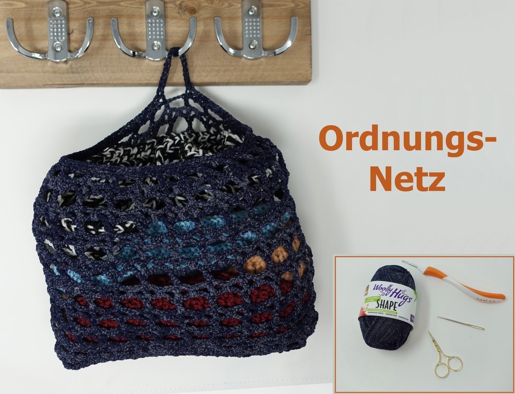 Dunkelblaues gehäkeltes Ordnungsnetz mit farbigen Akzenten an einer Garderobenleiste, daneben Garn und Häkelnadel