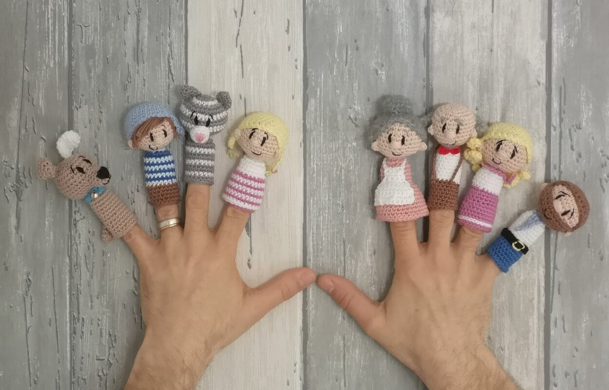 Reihe gehäkelter Amigurumi-Fingerpuppen auf zwei Händen als Inspirationssammlung