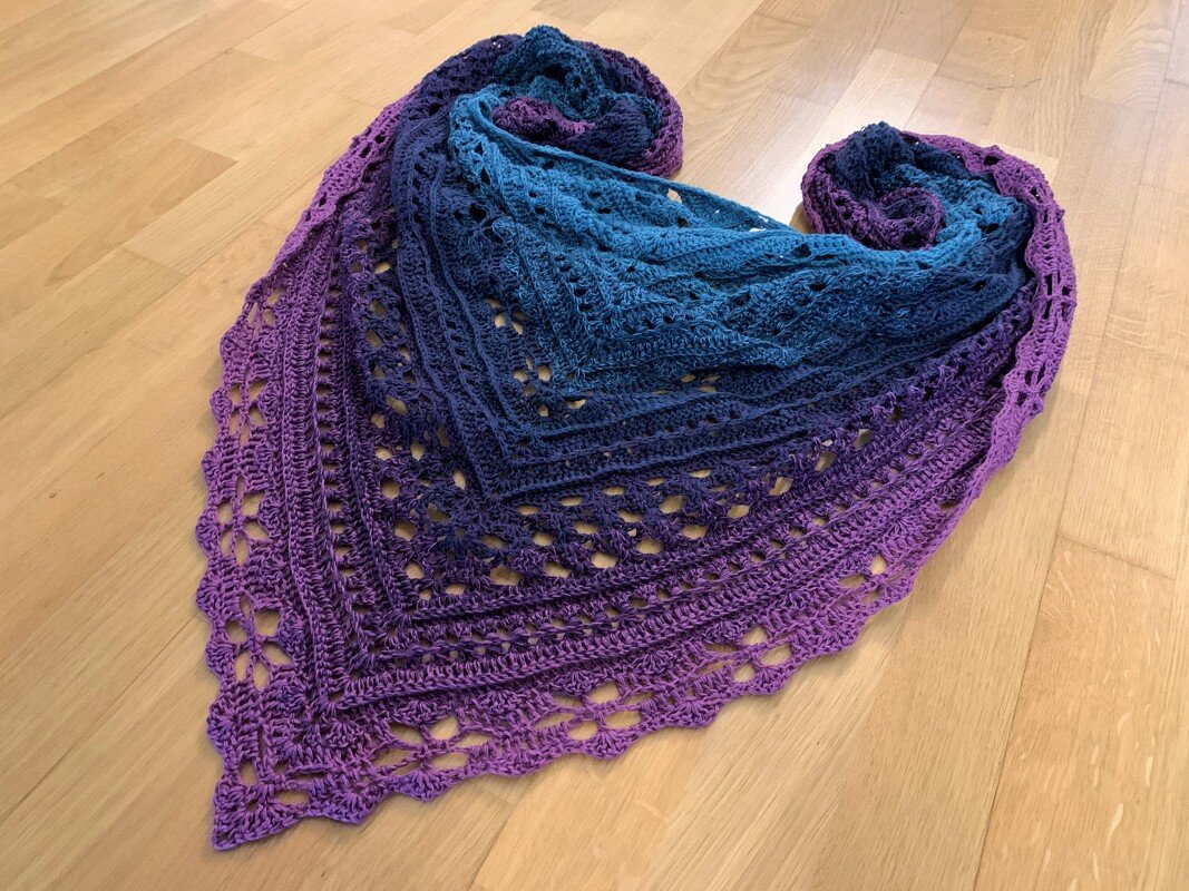 Detailansicht eines gehäkelten Dreieckstuchs mit Farbverlauf von Violett zu Blau und offenem Spitzenmuster