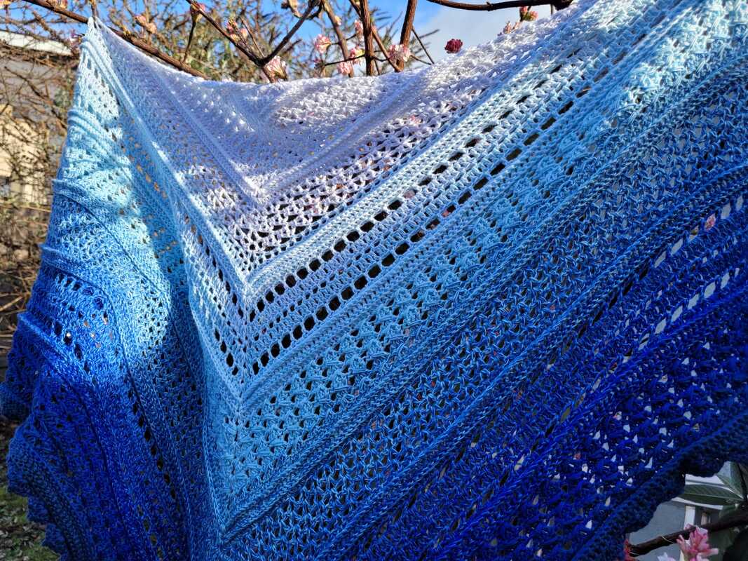 Gehäkeltes dreieckiges Tuch in abgestuften Blautönen mit Loch- und Spitzmustern