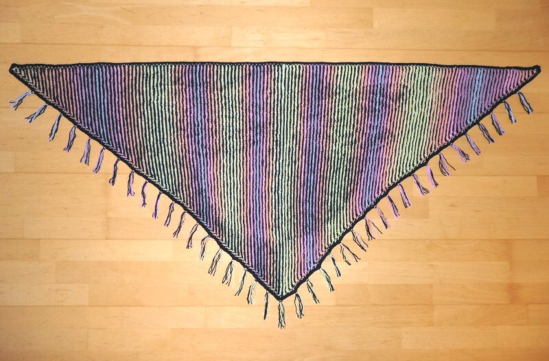 Gestricktes Dreieckstuch mit pastellfarbenen Streifen und Fransen auf Holzfußboden