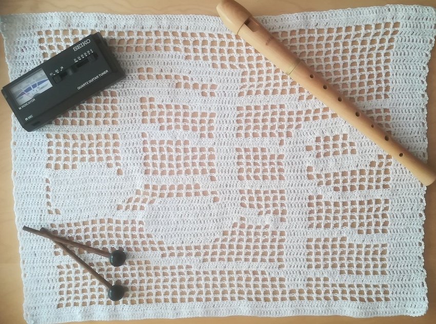 Weißes gehäkeltes Deckchen mit Blockflöte, Stimmgerät und Schlägeln