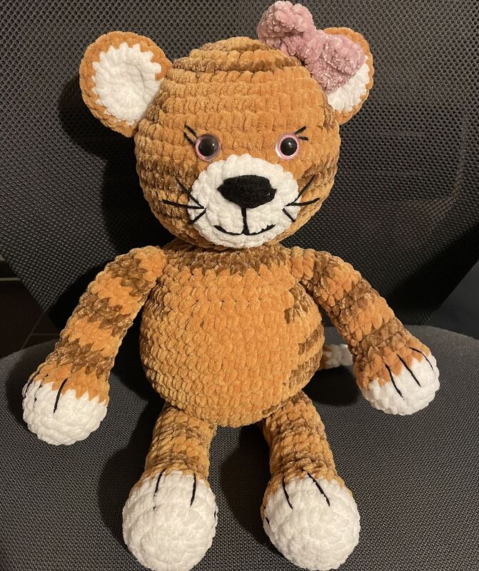 Gehäkeltes Amigurumi-Tiger Kuscheltier in orange-braun mit weißen Pfoten und rosa Schleife