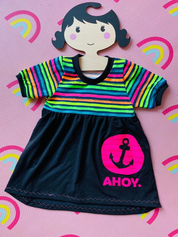 Kinderkleid mit neonfarben gestreiftem Oberteil und schwarzem Rock, pinker Anker mit Schriftzug ",AHOY" als Plottmotiv