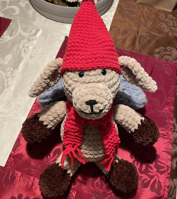 Beiges gehäkeltes Amigurumi-Kuscheltier mit roter Mütze, Schal und braunen Pfoten