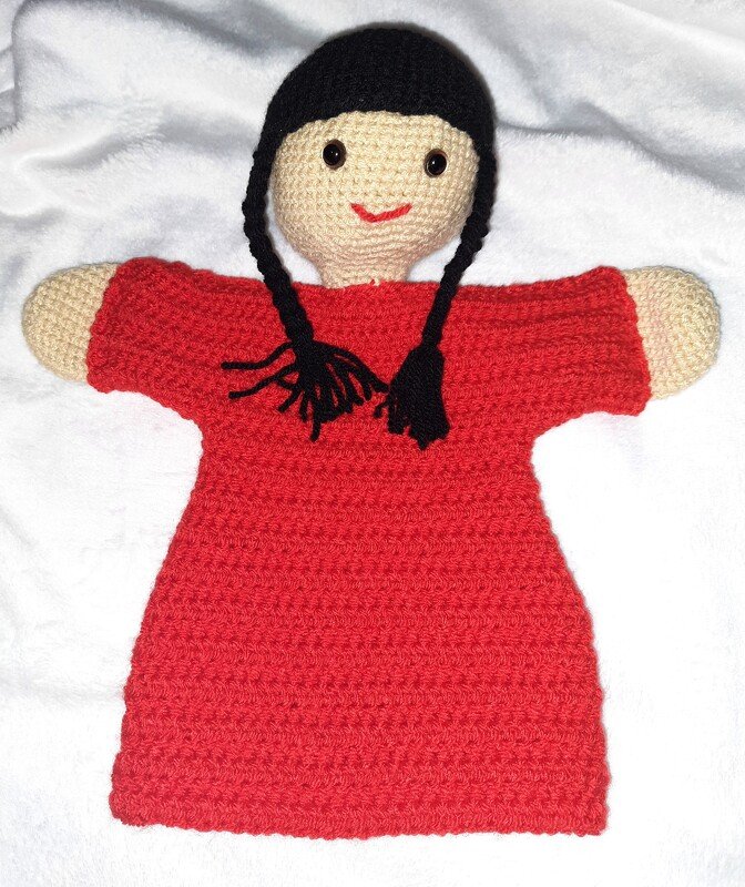 Gehäkelte Handpuppe in rotem Kleid mit zwei schwarzen Zöpfen