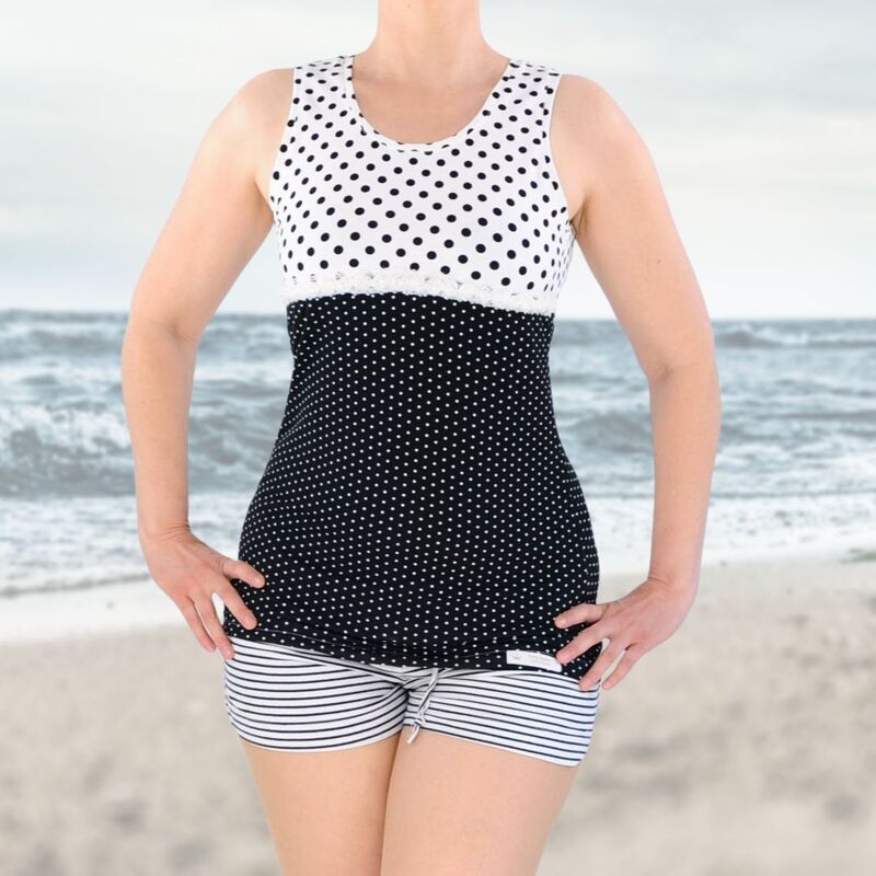 Schwarz-weiß gepunkteter Tankini mit gestreiften Shorts am Strand