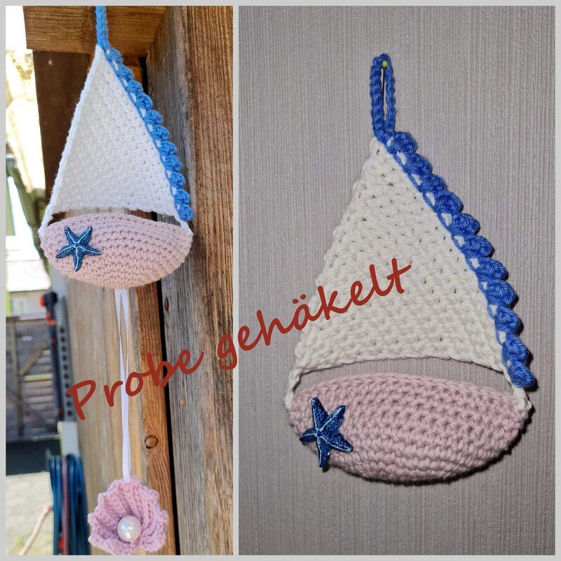 Gehäkelter Segelboot-Anhänger mit weißem Segel, rosa Rumpf und blauem Seestern