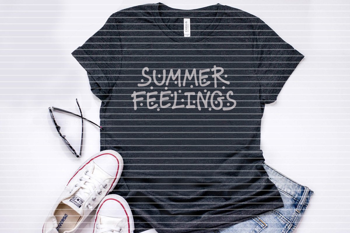 Dunkles T‑Shirt mit weißem Schriftzug 'SUMMER FEELINGS', daneben Sonnenbrille, weiße Sneakers und Jeans.