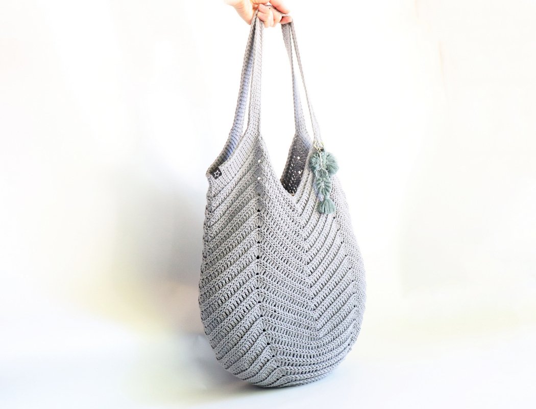 Light grey crochet shoulder bag with chevron stitch pattern and tassel charm