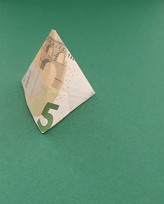 Gefaltete Pyramide aus einem 5‑Euro‑Schein auf grünem Untergrund