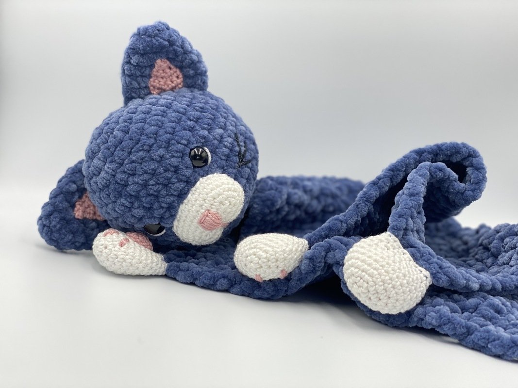 Plush blue crochet cat snuggle blanket with white face and paws