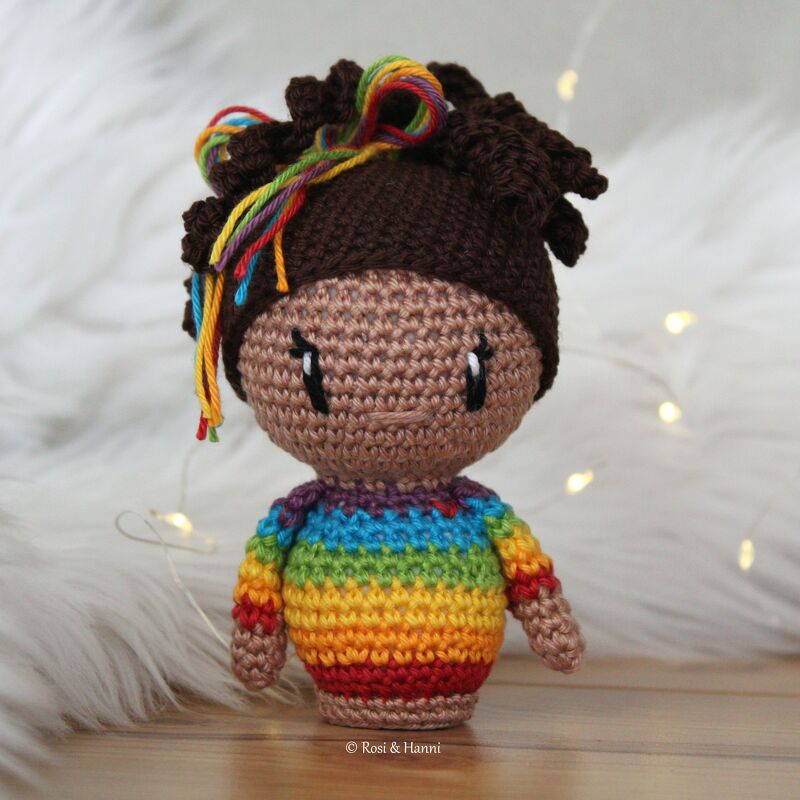 Gehäkelte Amigurumi-Puppe mit braunem Haar, bunten Haarsträhnen und gestreiftem Regenbogenpullover