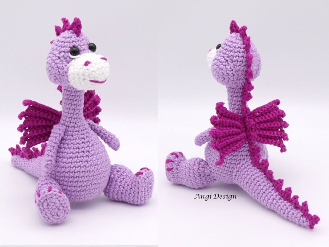 Gehäkelter sitzender Amigurumi-Drache in Lila mit magentafarbenen Flügeln vor hellem Hintergrund