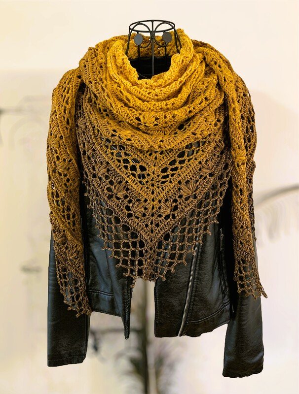 Ombre crocheted triangle shawl in mustard and brown with a lace pattern, draped over a black jacket on a mannequin.