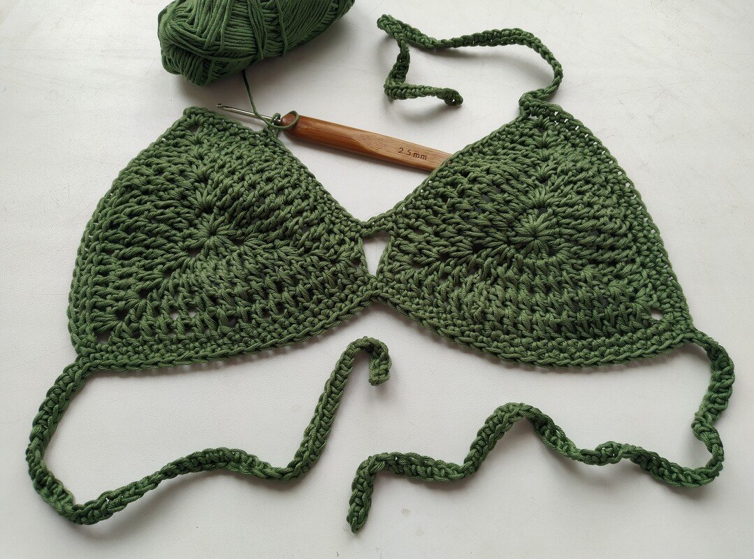 Green crochet triangle bikini top mid-project with 2.5 mm crochet hook and yarn ball