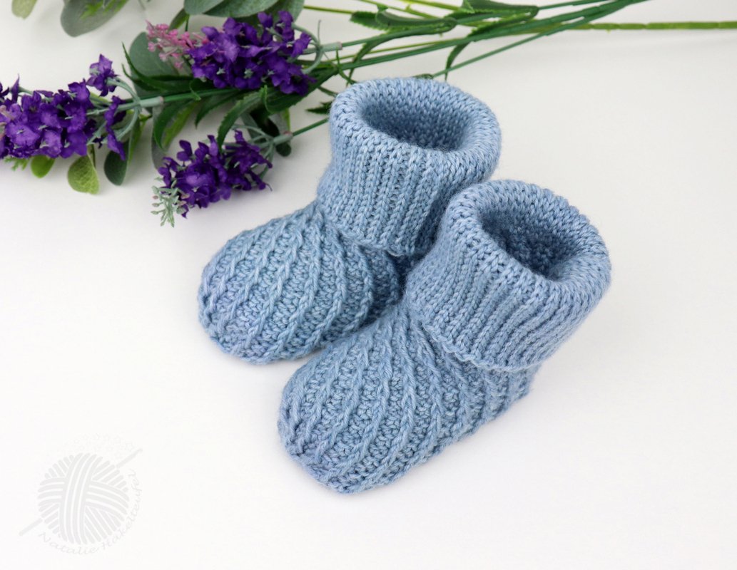 pair of light blue crochet baby booties with foldover ribbed cuffs on white background