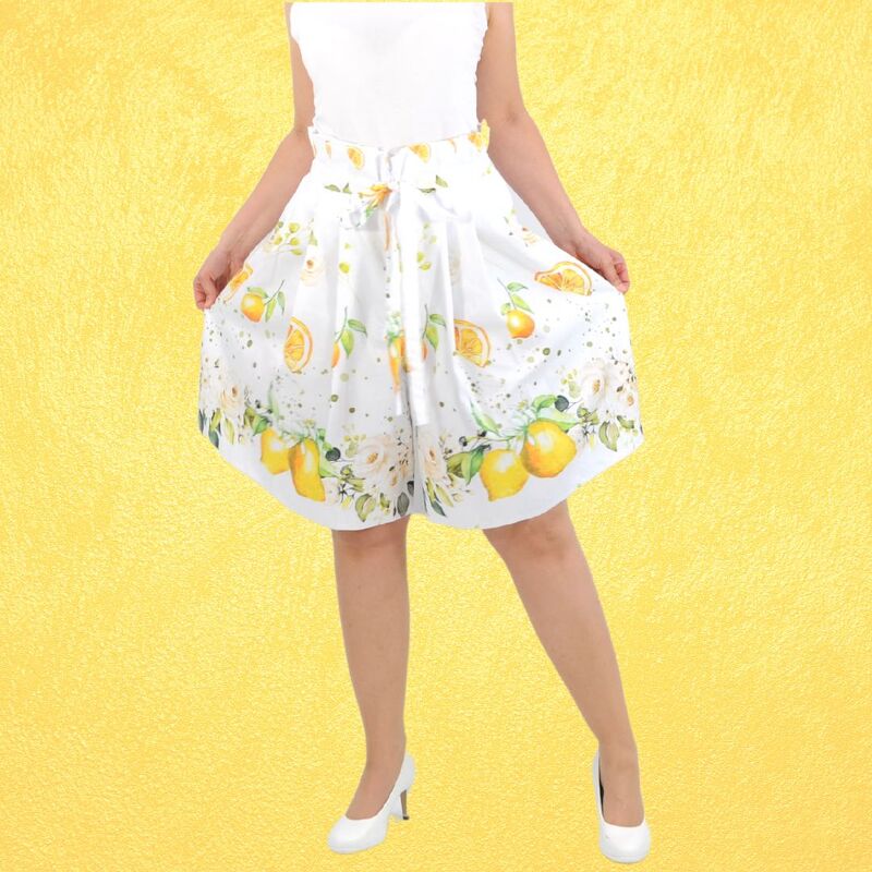 Weiße Culotte mit Zitronen- und Blumenmuster auf gelbem Hintergrund.