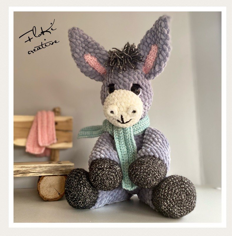Gehäkelter Amigurumi-Esel in Grautönen mit mintgrünem Schal, sitzend