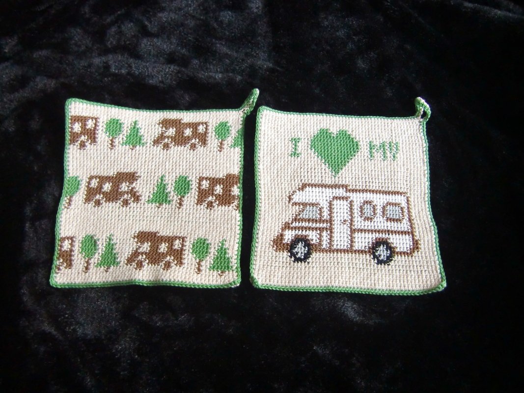 Zwei gehäkelte quadratische Topflappen beige mit grüner Kante; links wiederholtes Wohnmobil- und Baum-Muster, rechts einzelnes Wohnmobil mit Herz und Schlaufe