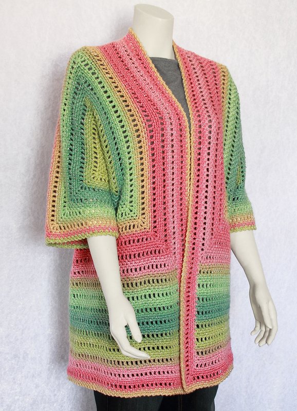 Mannequin wearing a pink, yellow and green gradient crochet open-front jacket with three-quarter sleeves