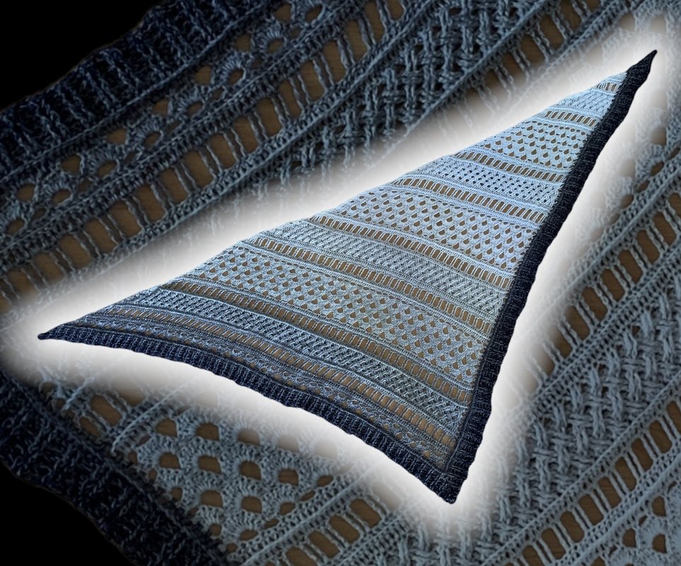 Close-up of crocheted triangle shawl showing eyelet motifs, mesh rows, and dark border