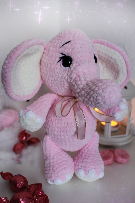 Rosa gehäkelter Amigurumi-Elefant mit Schleife und weißen Pfoten