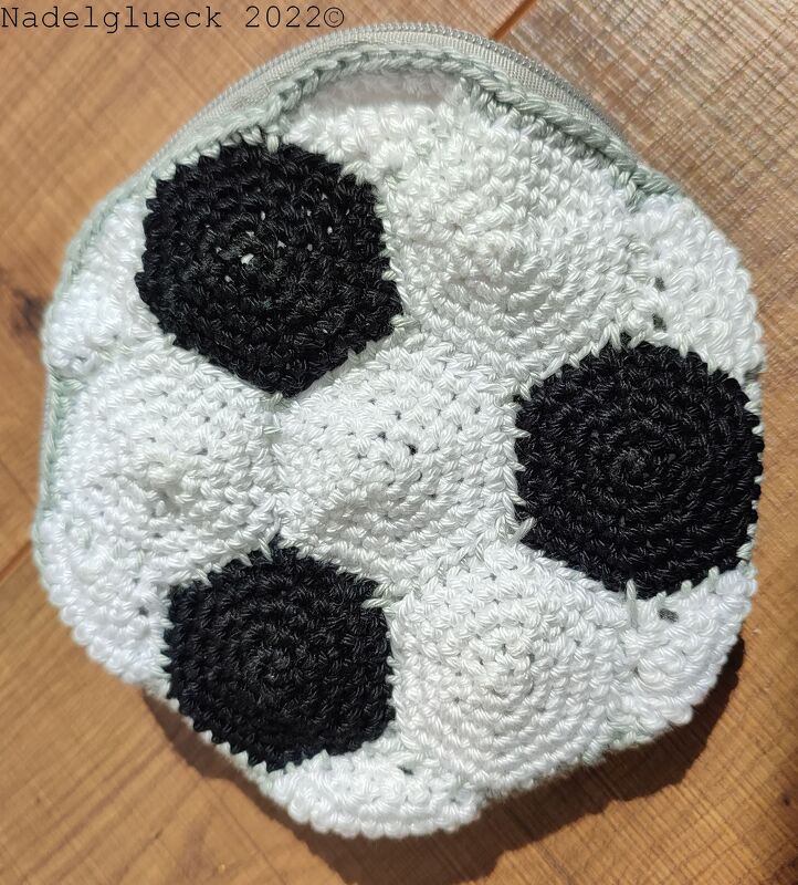 Rundes gehäkeltes Täschchen in Weiß mit schwarzen kreisförmigen Einsätzen und Reißverschluss
