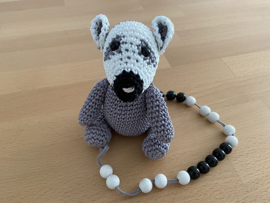 Gehäkeltes grau-weißes Amigurumi mit schwarz-weißer Perlenkette als Einschulungsgeschenk