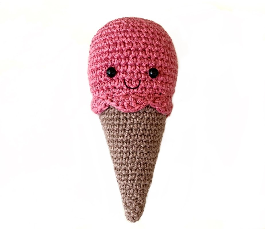 Gehäkelte Eistüte mit rosa Kugel, braunem Hörnchen und lächelndem Gesicht