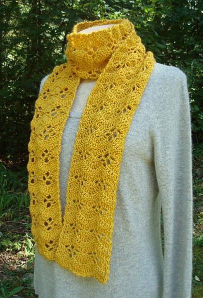 Mustard yellow crocheted lacy scarf draped on a mannequin wearing a light grey sweater