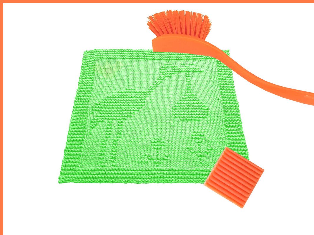 Leuchtend grünes Stricktuch mit Storchenmotiv, orangefarbene Spülbürste und geriffelte Seifenablage