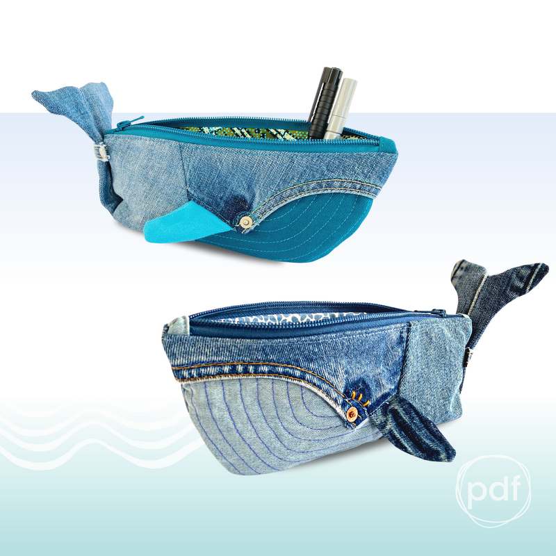 Two whale-shaped denim zipper pouches with tail and fin details; one pouch open showing pens inside