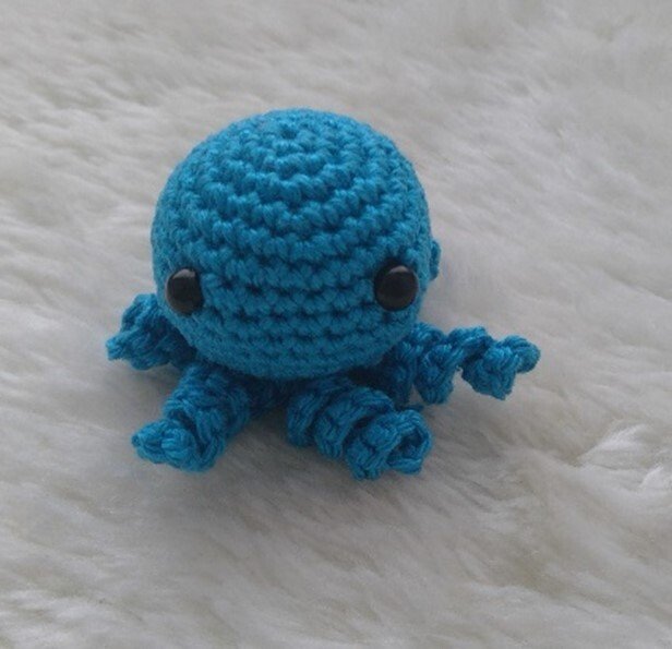 Kleiner türkisfarbener gehäkelter Oktopus mit schwarzen Augen