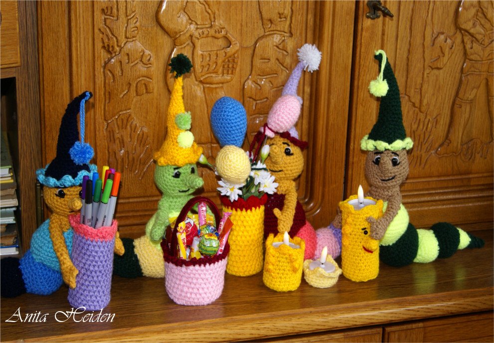 Bunte gehäkelte Amigurumi-Raupen mit Zipfelmützen, Stiftehalter, Körbchen, Blumenvasen und Kerzenhaltern.
