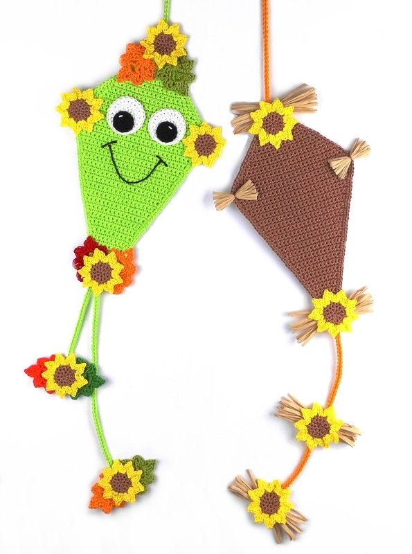 Zwei gehäkelte Drachen-Dekorationen mit Sonnenblumen, eine grün mit Gesicht, eine braun mit Raffia-Fransen