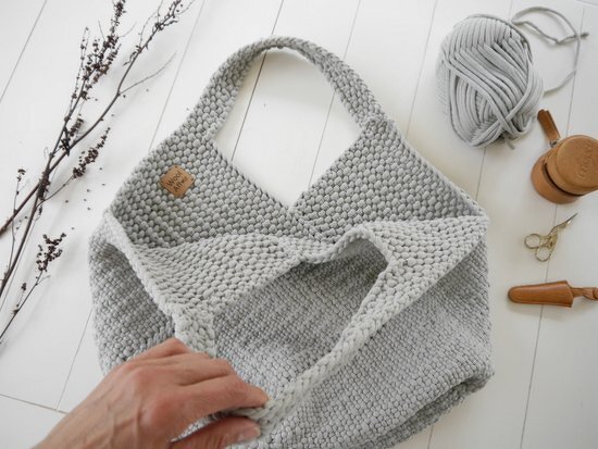 Hellgraue, grob gestrickte Shopper-Tasche mit Henkel und kleinem Lederetikett