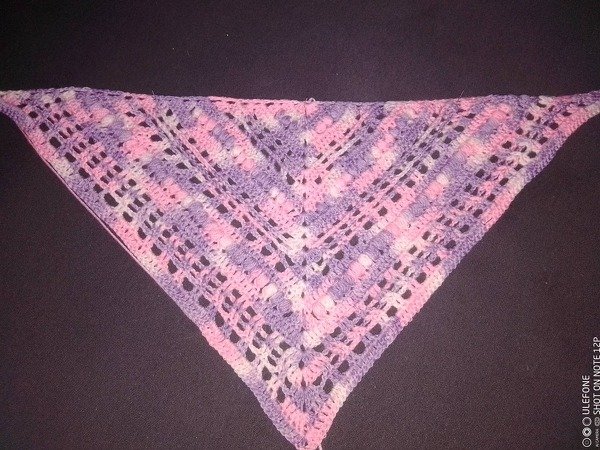 Gehäkeltes dreieckiges Tuch in rosa und lila Pastell mit Ajour‑ und Lochmuster auf dunklem Hintergrund