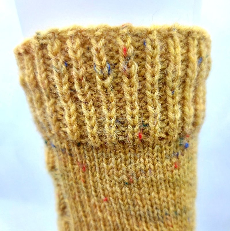 Gestrickter Sockenbund in Senfgelb mit bunten Tweed‑Sprenkeln, Rippenstruktur