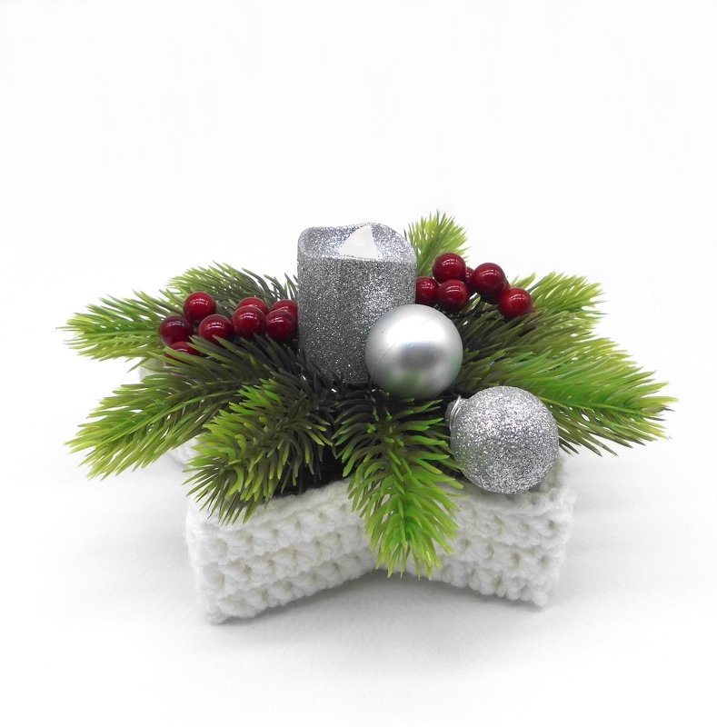 White crocheted star basket decorated with faux pine sprigs, red berries, a silver candle and silver ornament balls