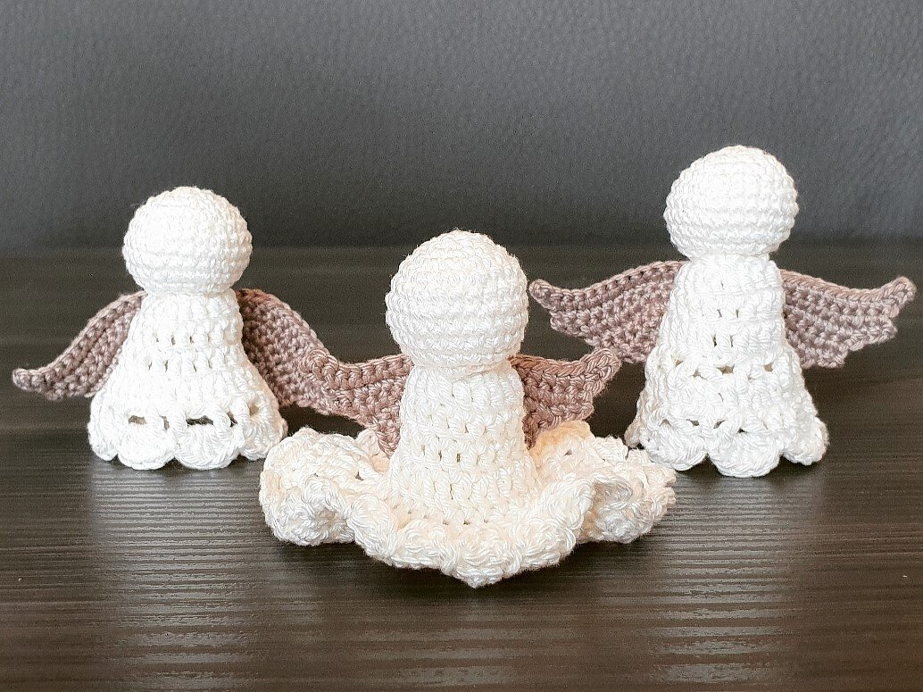 Drei weiße, gehäkelte Amigurumi-Engel mit hellbraunen Flügeln