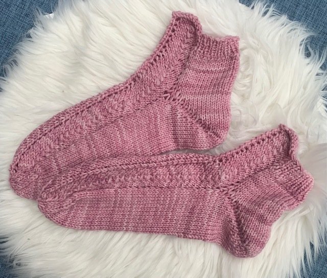 Nahaufnahme rosa gestrickter Kurzsocken mit Zopfkante und geformter Ferse