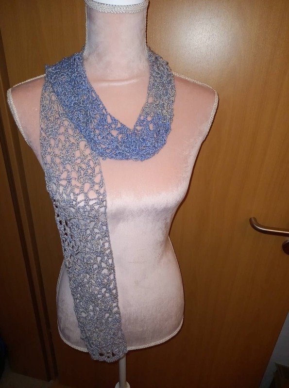 Gehäkelter Schal in Blau- und Grautönen mit offenem Lochmuster an einer Schaufensterpuppe