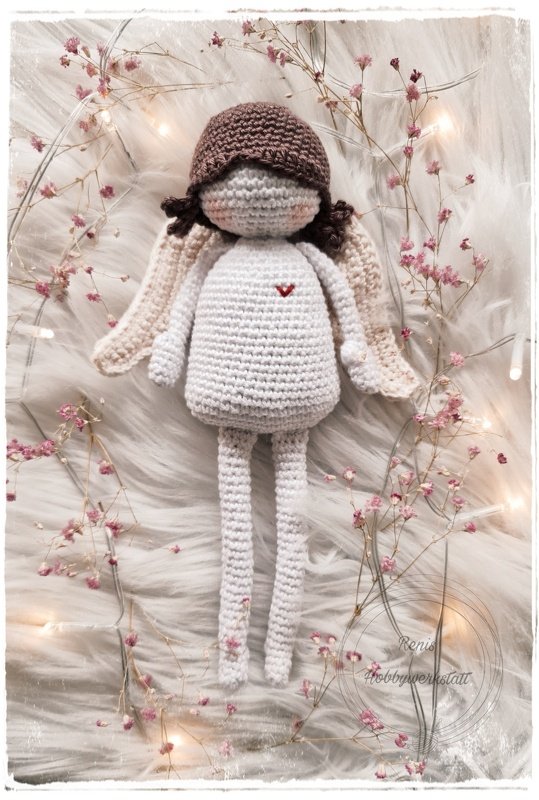 Gehäkeltes Amigurumi-Engelchen in Creme mit brauner Mütze und kleinem roten Herz