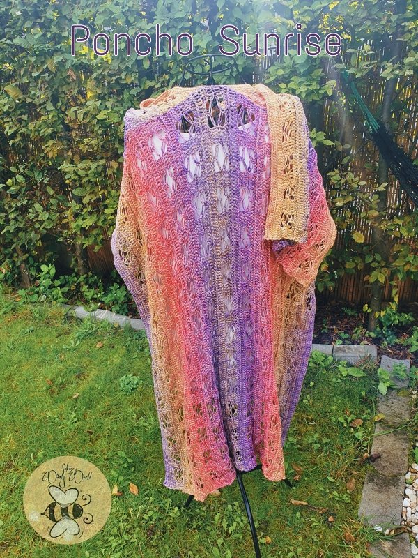 Gehäkelter Damenponcho mit Farbverlauf von Orange zu Violett auf Ständer im Garten