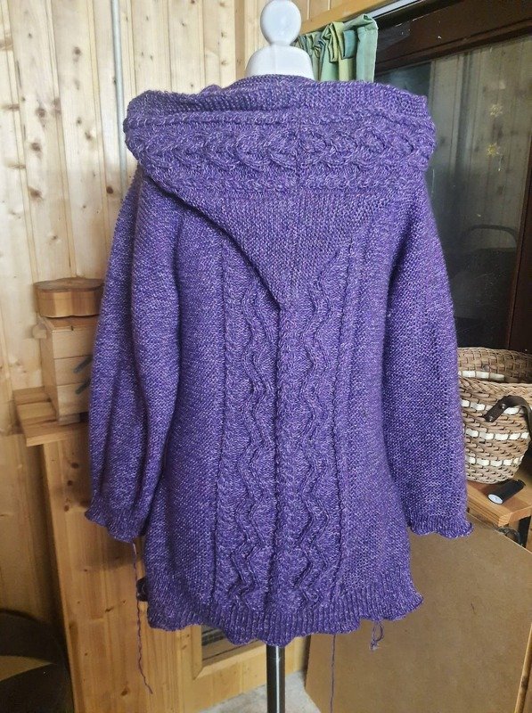 Lila gestrickte Damenjacke mit Kapuze und Zopfmuster, Rückansicht auf einer Schneiderpuppe
