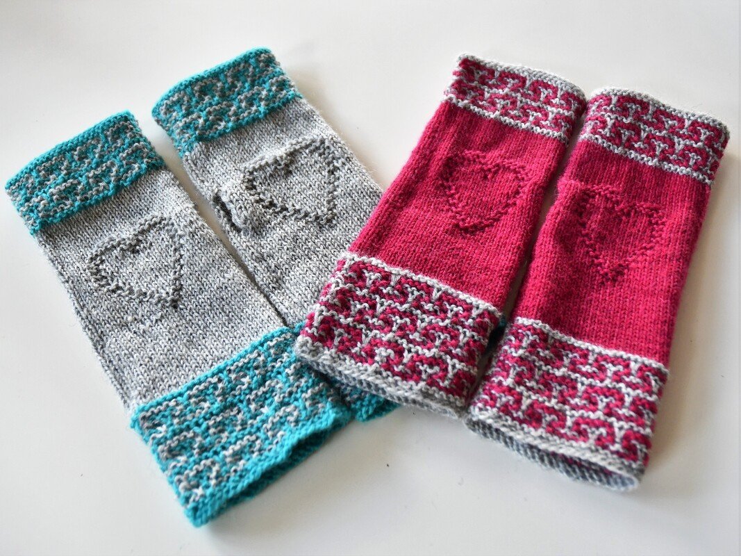 Zwei Paar gestrickte, fingerlose Armstulpen in Grau‑Türkis und Fuchsia mit Herzmotiven