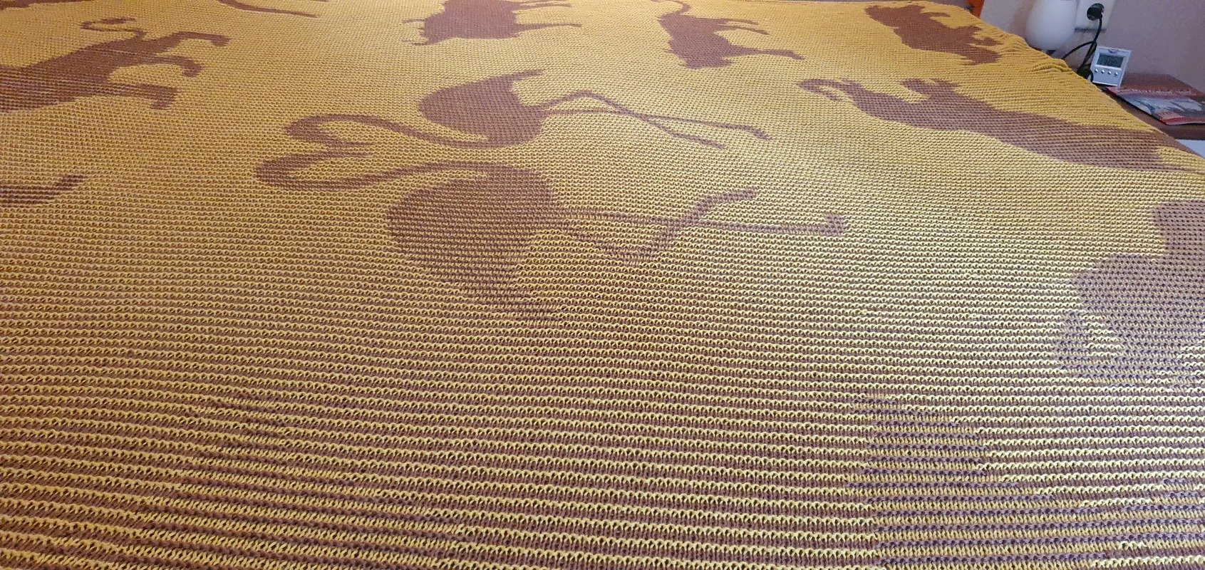 Mustard-yellow knitted blanket with brown horse silhouettes and horizontal rib stitch