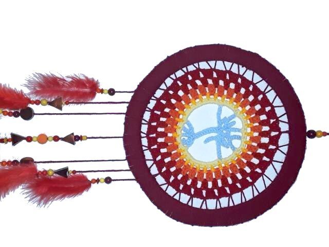 Crocheted circular wall hanging in red, orange, yellow and blue with beaded strands and red feather tassels.